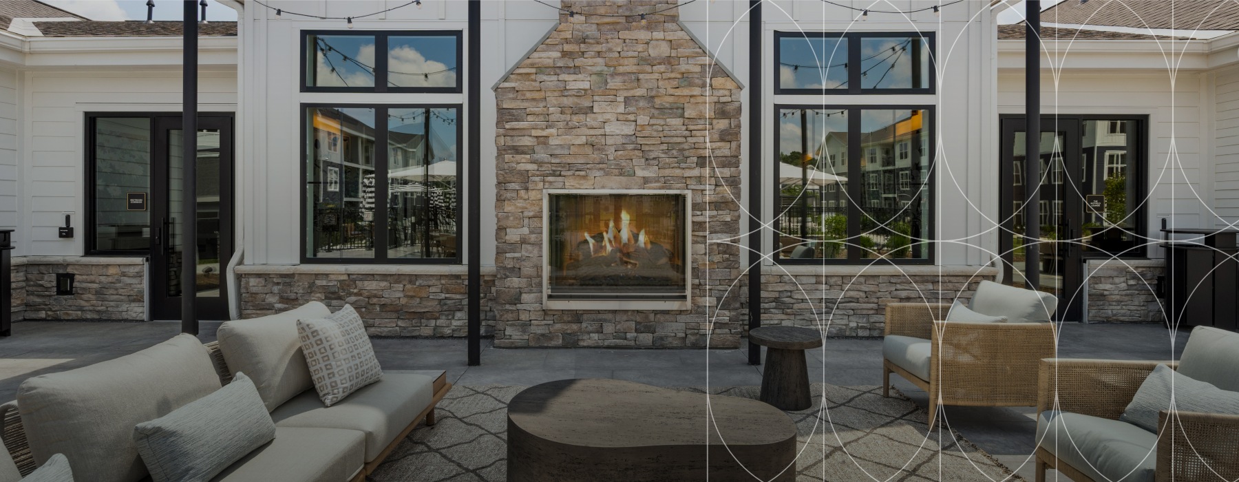 Outdoor lounge at Alta Oak and Pine apartments in Londonderry, NH, featuring a fireplace embedded in a stone masonry wall.