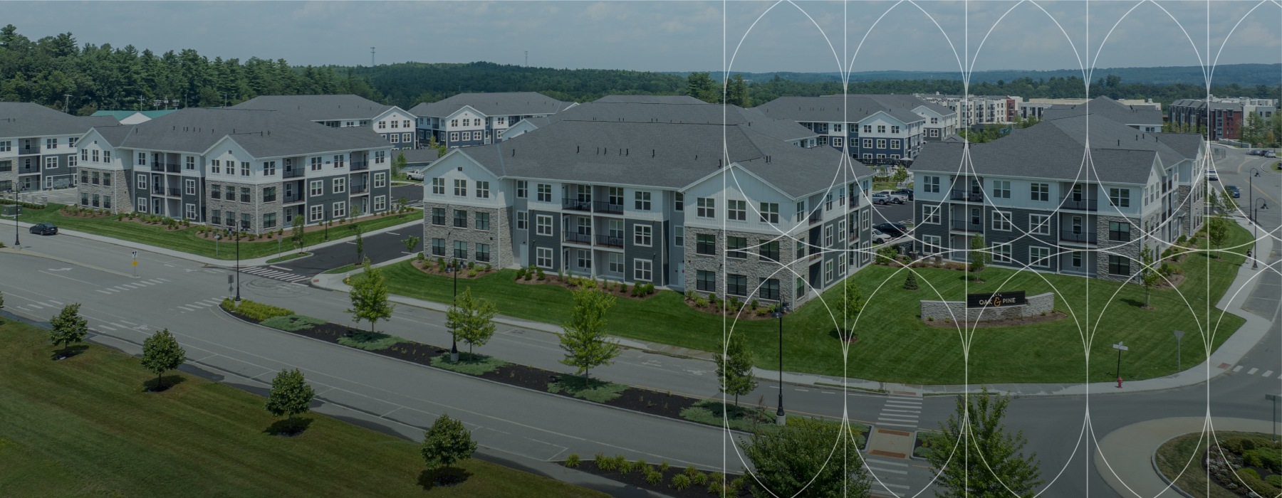 The exterior of Alta Oak and Pine apartments in Londonderry, NH, featuring a view of the streets and landscaped grounds.