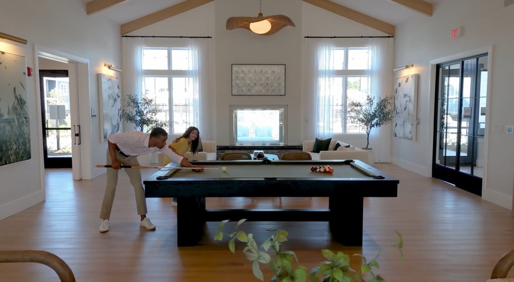 a person plays pool while a child watches